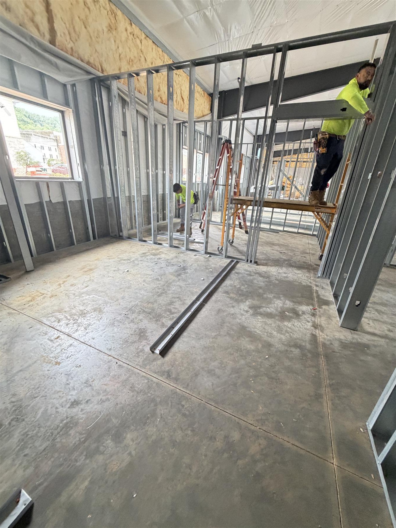 Drywall on the partitions and ceiling, with stacked sheets below, May 2026